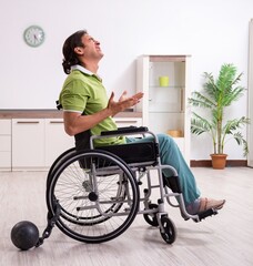 Young male invalid in wheel-chair suffering at home
