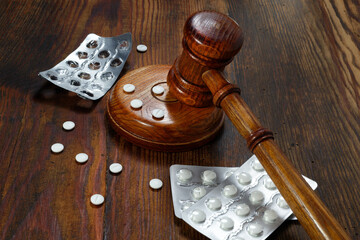 Law in medicine. Judge gavel and pills on a wooden background. Concept of medical law and medical...