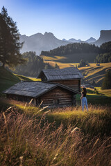 woman in front of old hut in the mountains during sunrise 