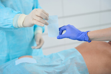 Fototapeta premium Assistant gives the surgeon plaster, they work in sterile condition