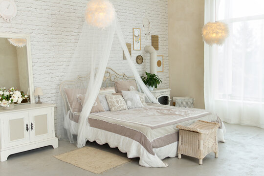 Comfortable simple bedroom with light-colored furniture, four-poster bed, feather lamps, small fireplace on wood, cosy modern place for rest and sleep