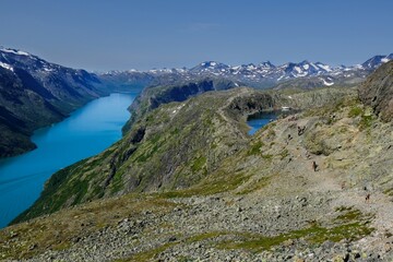 Fototapeta na wymiar Scenic Besseggen trail in Jotunheimen, Norway - the most beautiful trekking trail in Norway. Silhouettes of hiking tourists on trail.