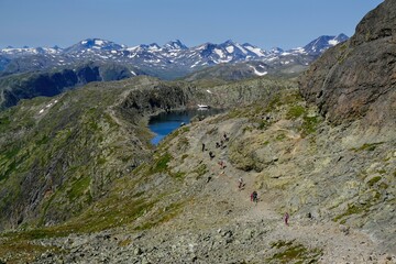 Scenic Besseggen trail in Jotunheimen, Norway - the most beautiful trekking trail in Norway. Silhouettes of hiking tourists on trail.
