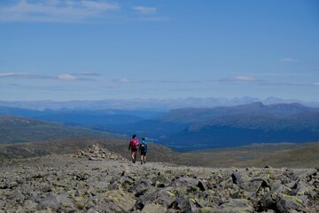 Fototapeta premium Scenic Besseggen trail in Jotunheimen, Norway - the most beautiful trekking trail in Norway. Silhouettes of hiking tourists on trail.