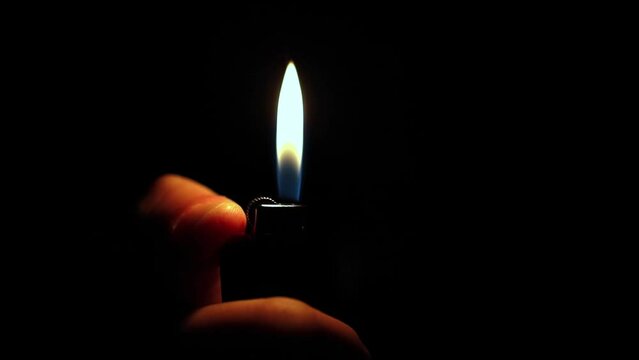 in hand a lighter with fire on a dark background