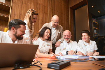 Group of smiling people in white coats is located in office