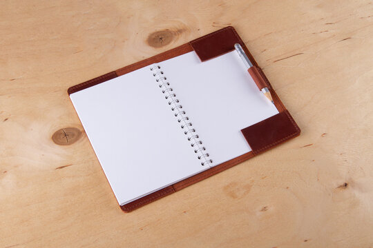 Blank scratchbook in leather cover with graphite pencil lie on wooden desk