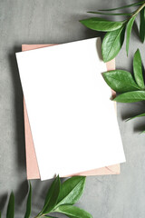 Mock up card with zamioculcas leaf. Invitation card with envelope on gray background