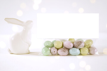 Party treat topper product mockup. Happy Easter theme product mockup. Minimal styling with bunny rabbit against a bokeh party lights background. Negative copy space.