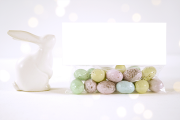 Party treat topper product mockup. Happy Easter theme product mockup. Minimal styling with bunny rabbit against a bokeh party lights background. Negative copy space.