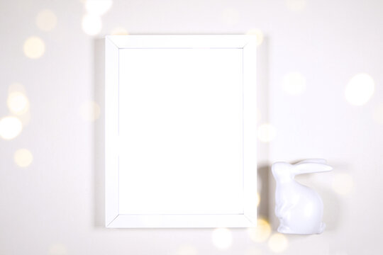 Artwork wall art picture frame product mockup. Happy Easter theme product mockup. Minimal styling with bunny rabbit against a bokeh party lights background. Negative copy space.
