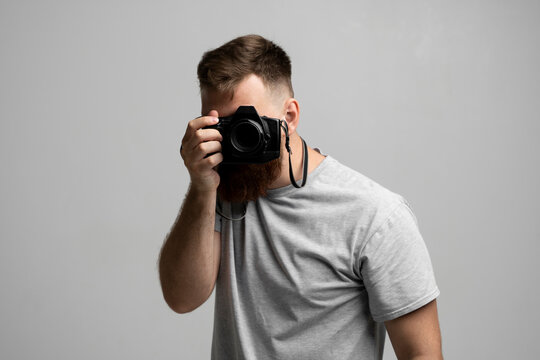 Professional bearded photographer holding a camera and ready to do a picture.