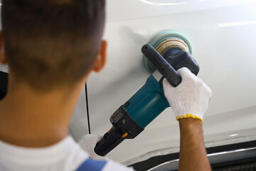 Close up photo of male polishing car in garage