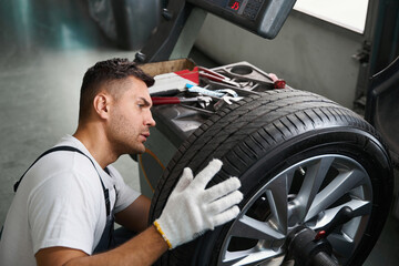 Worker checking technical condition of car wheel