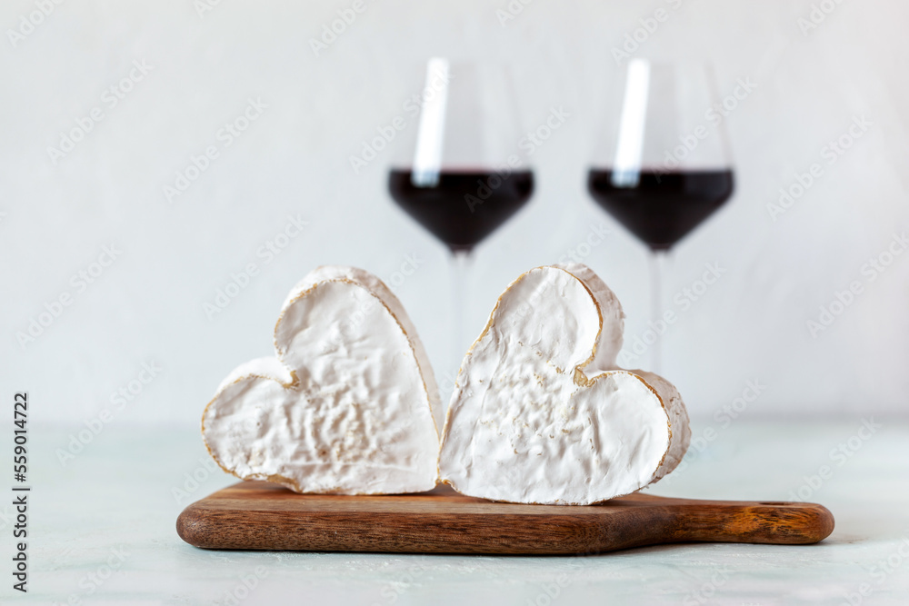 Wall mural soft heart shaped cheese and red wine glasses, valentine day concept