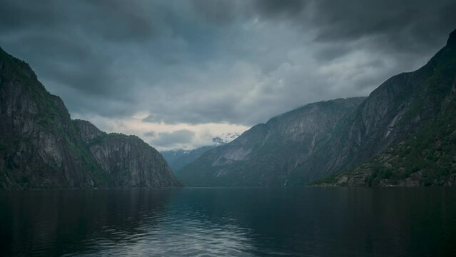 Timelapse video of sunset with last sunbeams in the fjord and mountain landscape Eidfjord in Norway, moving clouds in the sky and surface of water