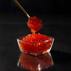 Caviar, A glass jar filled with red caviar with spoon of caviar, salmon caviar. Gourmet food, Delicious food concept, selective focus, dark background with reflection