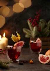 Composition with Two glasses of vitamin tea with grapefruit on brown background. two candles and garland bokeh