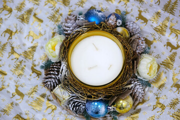 A large white candle, a New Year's candlestick with an original design,snow-covered cones, spruce twigs, blue Christmas balls,snowflakes, on a wooden stand,a view from above. A gift for the Christmas