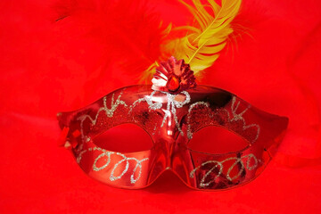 Carnival red mask with yellow feather on insulated red background horizontally
