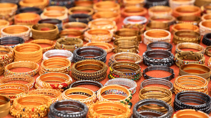 Several different bangles and bracelets are arranged for sale on the street side in India.