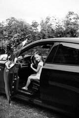 A little girl is sitting behind the wheel of a car, messing around and yelling at the photographer....
