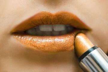 womans beautiful full lips with golden make up.applying lipstick.female mouth,white teeth.plump lips