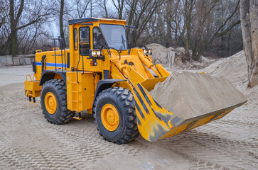 Wheel loader working in a gravel pit. Mining machines moving clay, smoothing the surface of gravel for a new road. Earthworks, excavations, digging in the ground, loading of charging baskets