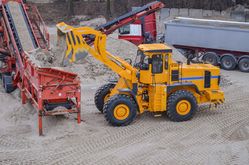 Wheel loader working in a gravel pit. Mining machines moving clay, smoothing the surface of gravel for a new road. Earthworks, excavations, digging in the ground, loading of charging baskets