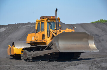 Crawler bulldozer with a large roller for compaction on a coal heap. 