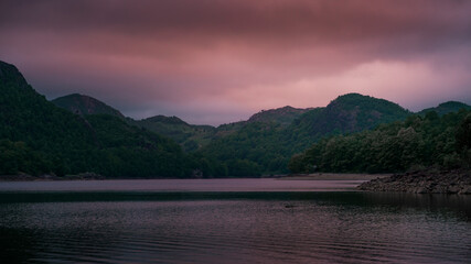Cloudy purple sunset on calm lake with mountains in Norway near Stavanger