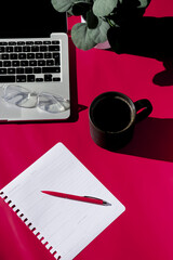flat lay composition of empty notebook, coffee, computer and glasses on magenta background 