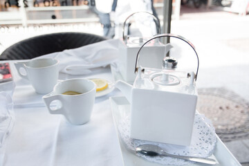 Fototapeta na wymiar tea break with a white tea set at a table in a cafe in the city