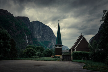 Church in Lysebotn surrounded by mountains in Norway, dark clouds in the sky