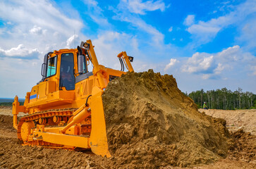 Crawler bulldozer working on construction site or quarry. Mining machinery moving clay, smoothing gravel surface for new road. Earthmoving, excavations, digging on soils - obrazy, fototapety, plakaty