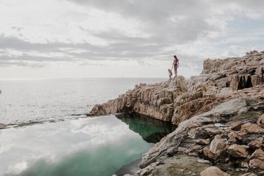 Mother with son at swimming pool on rocky seashore, Costa Brava, Catalonia, Spain
