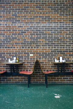 Diner Booth Seats Against A Brick Wall With A Green Linoleum Floor.