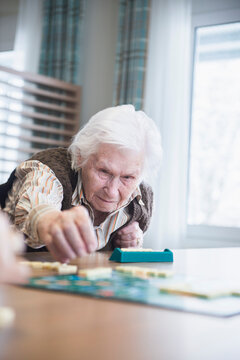 Senior woman playing board game in rest home