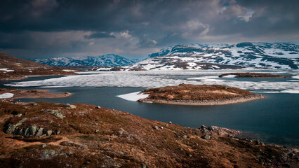 Snowy landscape of Hardangervidda national park with mountains and icy lakes in Norway, from above