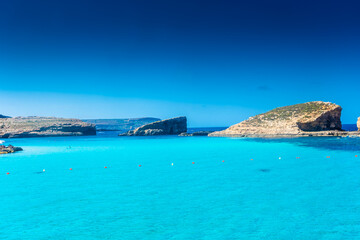 Comino, Malta, 22 May 2022:  Tourists swimming in the crystal clear water of the Blue Lagoon