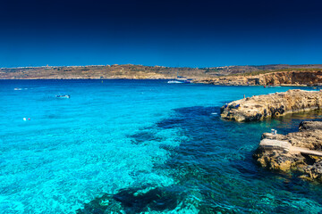 Fototapeta na wymiar Comino, Malta, 22 May 2022: Tourists swimming in the crystal clear water of the Blue Lagoon