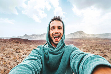 Handsome man taking selfie photo with smart mobile phone device outside - Cheerful climber hiking...