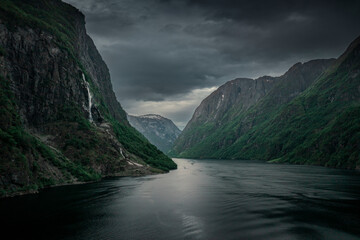 Moody fjord with mountains and waterfall of Aurlandsfjord at Gudvangen in Norway, dark clouds in the sky, from above - 559032539