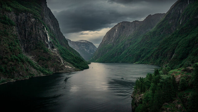 Moody fjord with mountains and waterfall of Aurlandsfjord at Gudvangen in Norway, dark clouds in the sky, from above