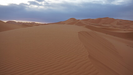 Fototapeta na wymiar Landscape of sand dunes with distinct, sharp ridges on a moroccan Sahara erg, near the settlement of Merzouga.