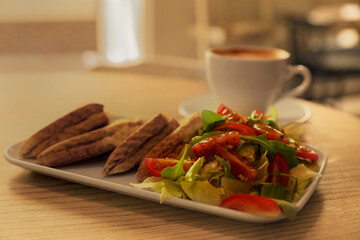 Plate of delicious toasts with salad and coffee cup on wooden table in cafe, closeup