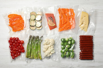 Different food products in vacuum packs on white wooden table, flat lay - obrazy, fototapety, plakaty