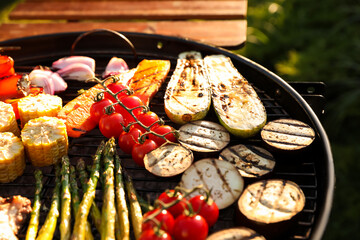 Delicious grilled vegetables and meat on barbecue grill outdoors, closeup