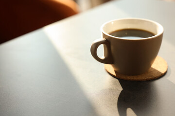 Cup of delicious coffee on grey table indoors, closeup. Space for text