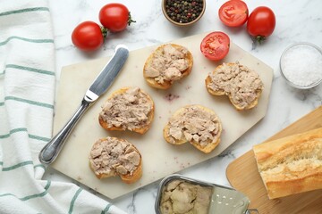 Tasty sandwiches with cod liver on white marble table, flat lay
